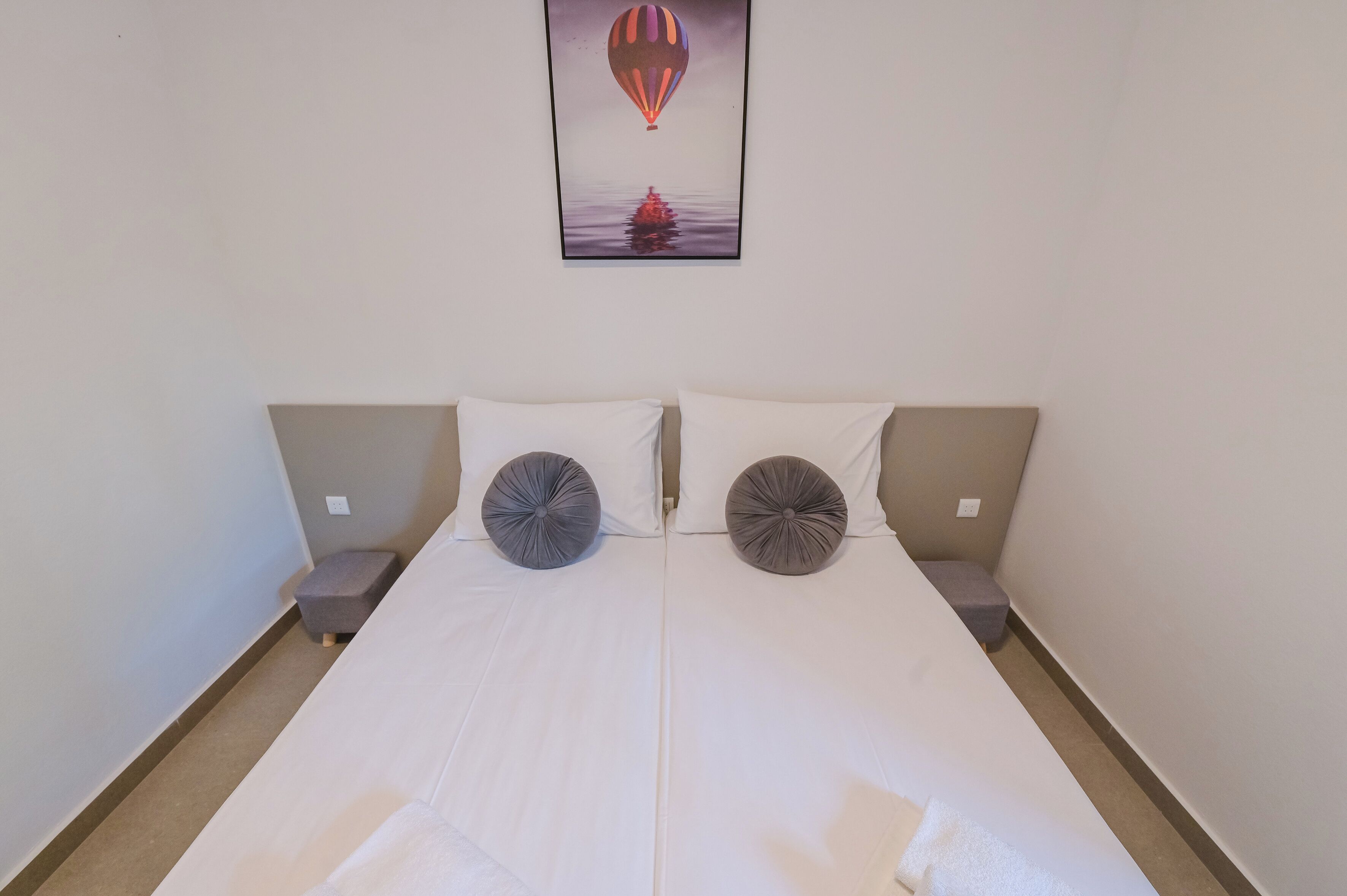 A double bed with two pillows, a nightstand on each side, and a framed picture above the bed.