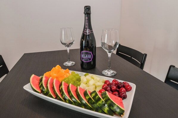 A table with a bottle of Rose wine, two glasses, and a fruit platter.