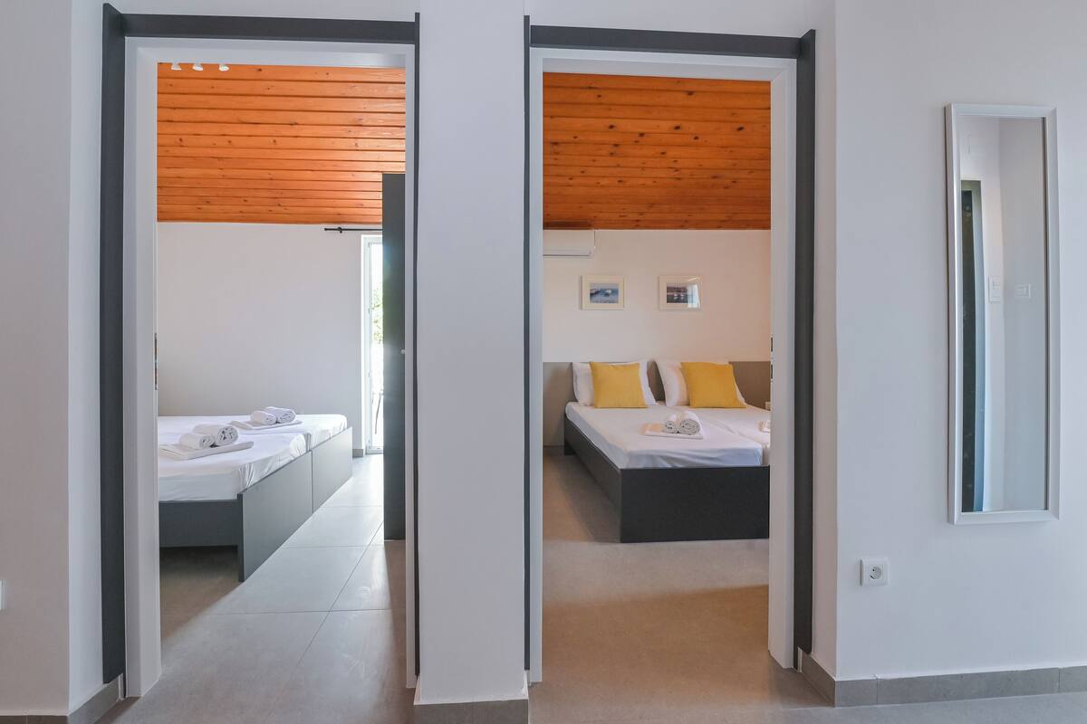 A hotel room with a bed, a bedside table, and a view through an open door.