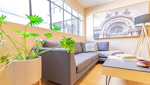 A modern living room with a gray sofa, a wooden coffee table, and a large window with a view of a building. - Hidden gem near WTC | Bright & Chic (Ciudad de México)
