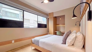 Une chambre moderne avec un lit en bois, une grande fenêtre et un ventilateur de plafond.