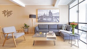 Un salon moderne avec un canapé gris, une table basse, un lampadaire et un tableau représentant un paysage urbain.