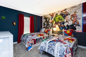 Een slaapkamer met twee bedden, een groot wanddecor en een wit bureau.