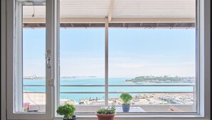 A window with a view of a coastal cityscape, two potted plants on the windowsill, and a small tray with items. - A MILLION DOLLAR VIEW IN THE HEART OF ISTANBUL (İstanbul)