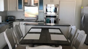 Una cucina moderna con isola centrale, elettrodomestici integrati e zona pranzo con tavolo e sedie.