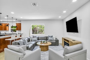 A modern living room with a sectional sofa, a coffee table, and a TV mounted on the wall. - Private Heated Pool · Sleeps 8 · Pets Welcome · Boca Raton (Boca Raton)