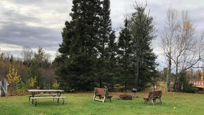 A grassy park area with picnic tables and benches.