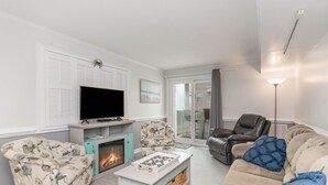 A living room with a fireplace, a television, a sofa, and a coffee table. - Oceanfront Holiday Getaway (North Myrtle Beach)
