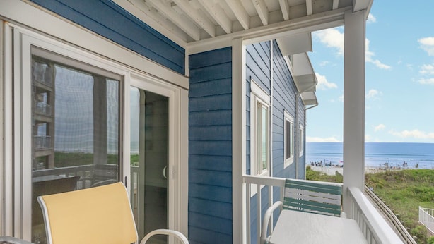 A balcony with a view of the beach, a table, and two chairs. - Oceanfront Holiday Getaway (North Myrtle Beach)