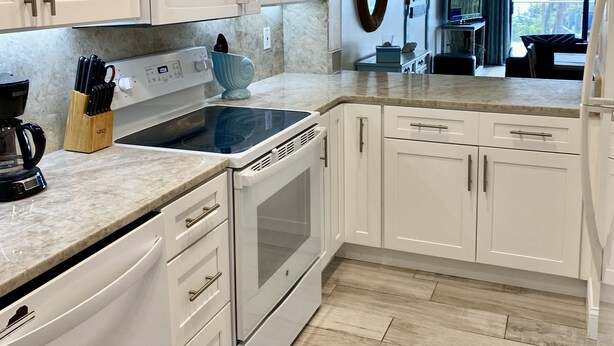 A modern kitchen with white cabinetry, a built-in microwave, and a large oven. - Beachfront (Cape Canaveral)