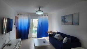 A living room with a TV, a sofa, a coffee table, and a ceiling light. - Modern Apartment (Juan Dolio)