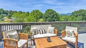 Une terrasse dotée de mobilier d’extérieur, comprenant des chaises et une table, qui offre une vue imprenable sur un paysage pittoresque, avec des arbres et des montagnes.