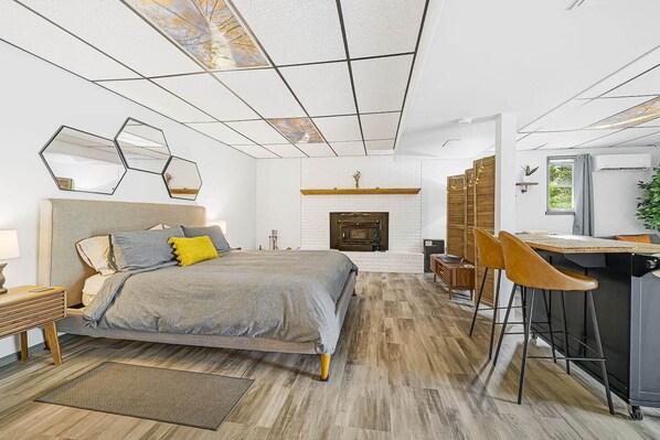Un dormitorio moderno con una cama grande, una chimenea, un escritorio con sillas y vistas al exterior a través de un tragaluz.