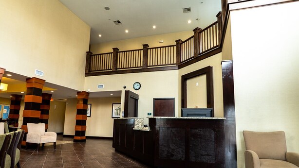 Un hall d’entrée avec un comptoir de réception, une horloge et un escalier.