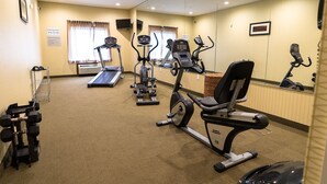 Une salle de sport d’hôtel équipée de tapis de course, de vélos elliptiques et d’appareils de musculation.