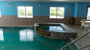 Une piscine intérieure avec des murs carrelés et une vue dégagée sur l’extérieur grâce à de grandes fenêtres.