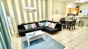 A living room with a black sofa, a white coffee table, and striped wallpaper. - Amazing 3/2 Townhome With Lake View at Terra Verde!! (Kissimmee)