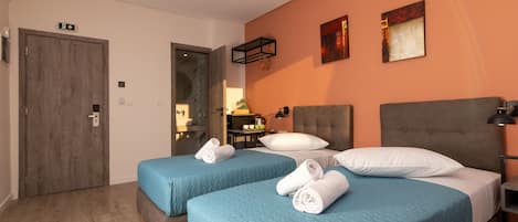 Habitación de hotel con dos camas, una puerta de madera y un cuadro en la pared.