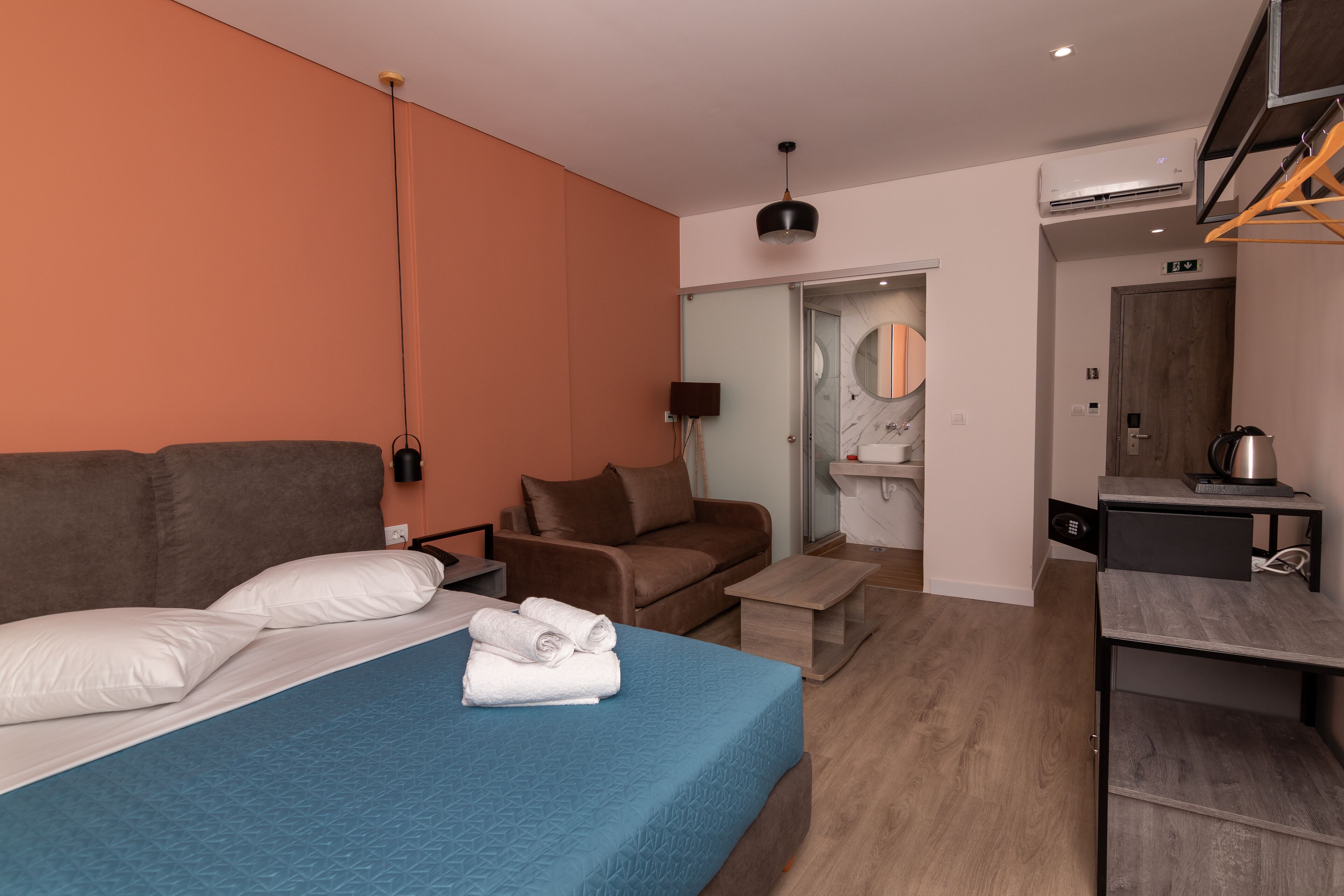 Una camera d'albergo moderna con un letto, una poltrona, un tavolino e una scrivania.