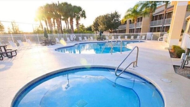 Una piscina circular con una escalera metálica, rodeada de sillones de descanso y una valla.