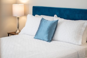 Restful retreat with a neatly made bed and a bedside table featuring a lamp.