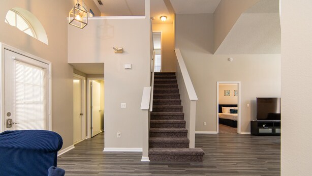 A spacious living area with a carpeted staircase, a sofa, and a television. - Private Pool, Close to Disney!!! (Kissimmee)