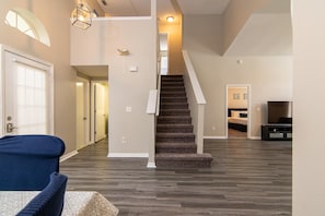 Stairs lead to an upper level in this inviting space with a carpeted staircase and dark wood flooring.