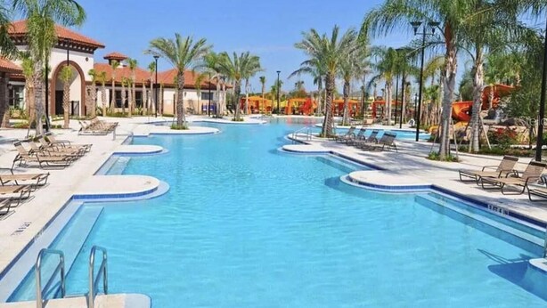 A large swimming pool with multiple lanes, surrounded by palm trees and lounge chairs. - Solterra Resort!! Spacious House With Game Room, Private Pool and Movie Room!! (Davenport)