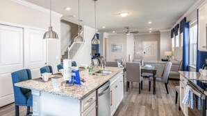A modern kitchen with granite countertops, stainless steel appliances, and blue chairs. - Amazing 5/6 Vacation Home at Windsor Island Resort!!! (Davenport)