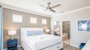 A bedroom with a bed, two bedside tables with lamps, a ceiling fan, and a bathroom visible through an open door. - Amazing 5/6 Vacation Home at Windsor Island Resort!!! (Davenport)