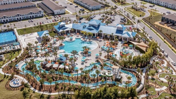 An aerial view of a resort with a large central pool, multiple smaller pools, and a variety of outdoor seating areas surrounded by palm trees. - Amazing 5/6 Vacation Home at Windsor Island Resort!!! (Davenport)