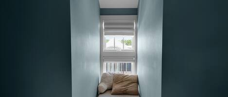 A narrow room with a window, a bed, and two pillows.