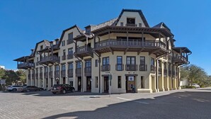 A multi-story hotel with balconies, a cobblestone courtyard, and a clear blue sky.