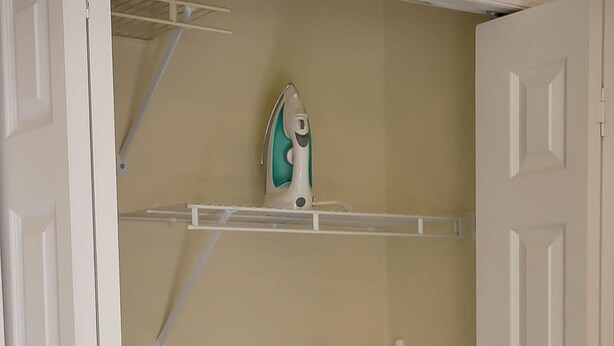 Un armadio con un appendiabiti, un asse da stiro e un ferro da stiro.