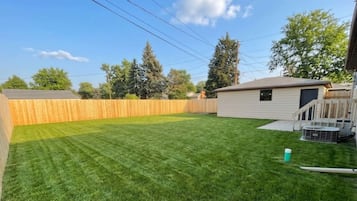 A backyard with a wooden fence, a lawn, and a small shed.