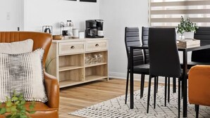 A modern living room with a brown leather sofa, a coffee table, and a dining area with black chairs and a wooden table. - 3 Bed 2 Bath, Golf Course and Fully Fenced Yard! (Rapid City)