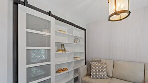 Un soggiorno con un divano color beige, una porta scorrevole in vetro con mensole e un lampadario.