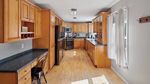 Una cucina con mobili in legno, un piano di lavoro in granito, un frigorifero e un forno a microonde.