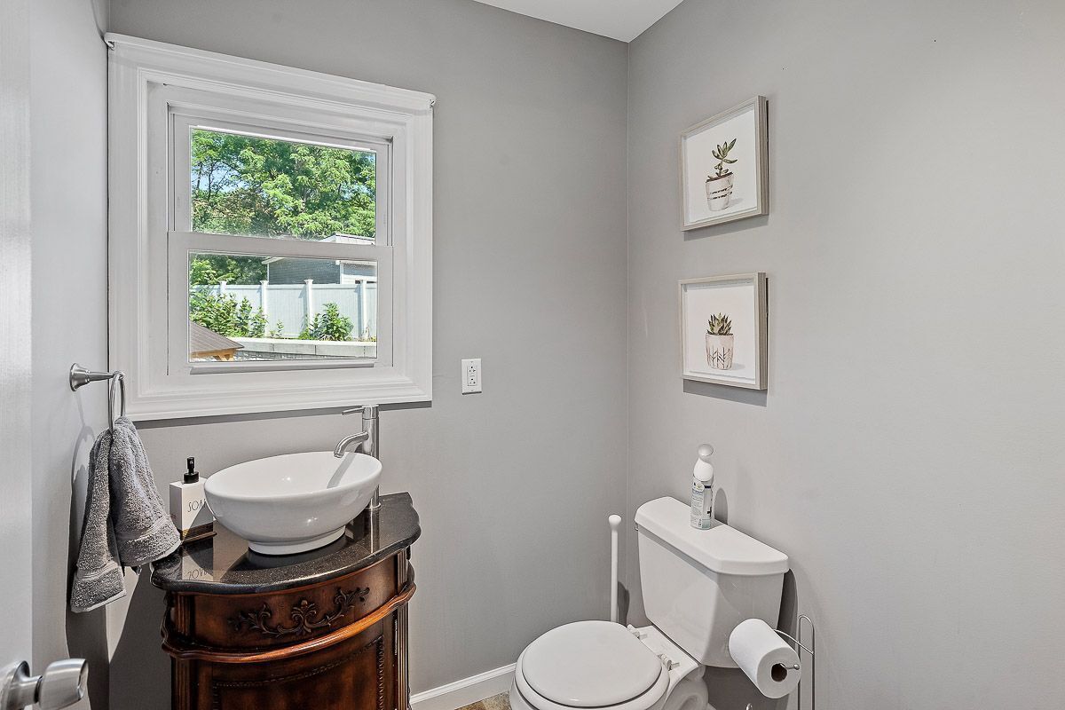 A bathroom with a white sink, a toilet, and framed pictures on the wall.