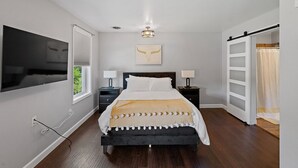 Una camera da letto con un letto, una TV a parete, una lampada a soffitto e una finestra.