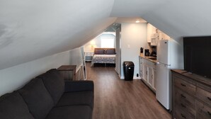 A compact, modern apartment with a kitchenette, a sofa, and a bed in the background. - Harrison Hotel  Unit G2 Pet Friendly  STEEP STAIRS! 3rd story Studio apartment.
 (Garden City)