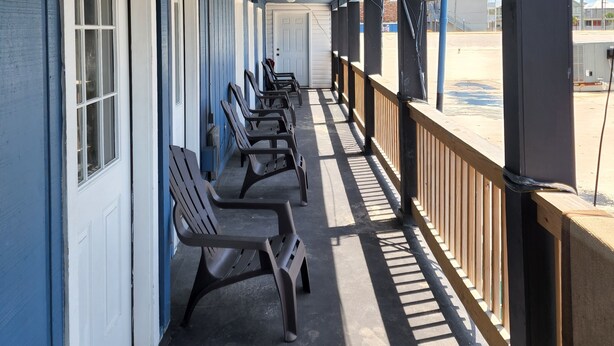 A covered porch with rows of chairs and a view of the parking lot. - Harrison Hotel  Unit G2 Pet Friendly  STEEP STAIRS! 3rd story Studio apartment.
 (Garden City)