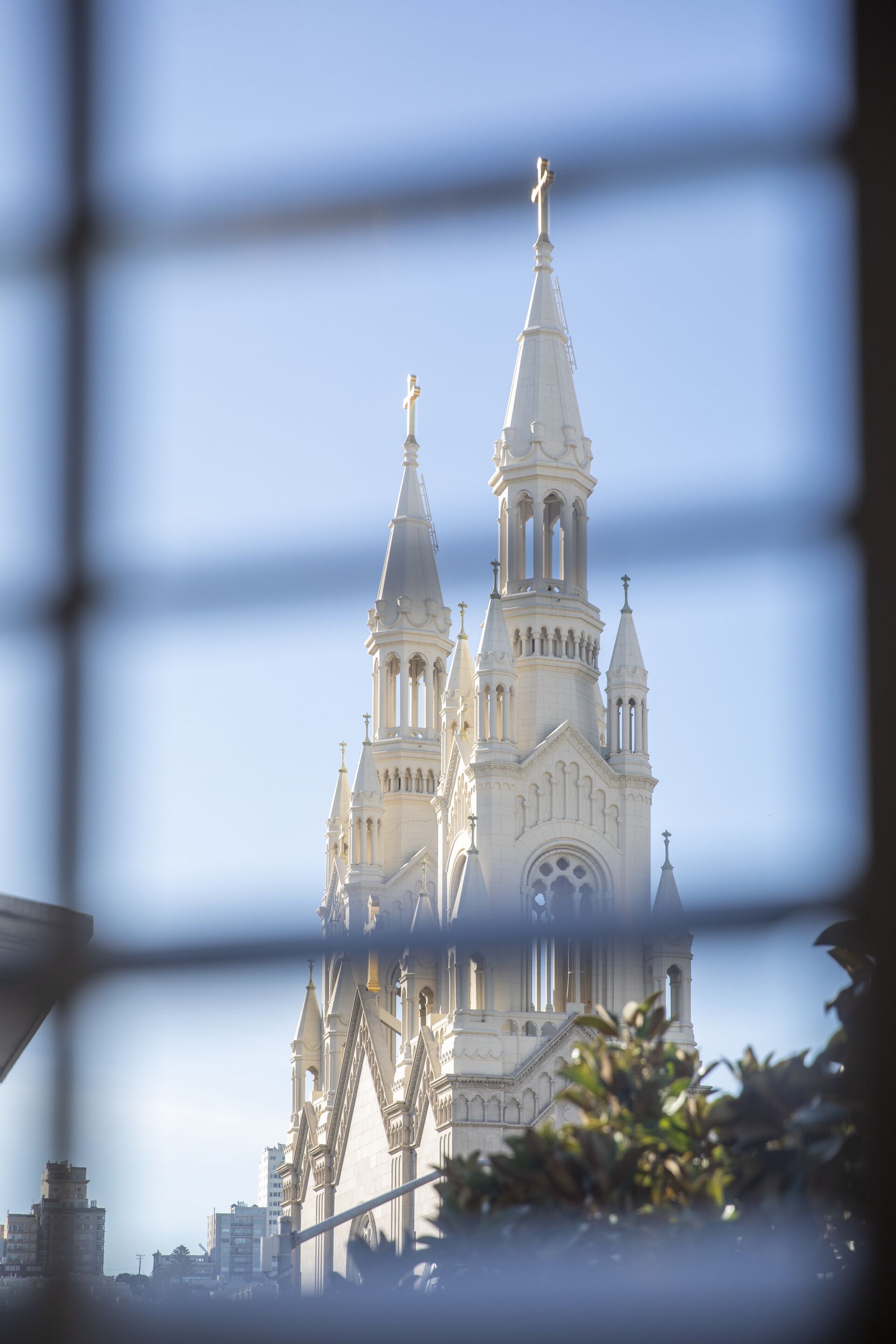 A cathedral with multiple spires and a prominent central tower, viewed through a window with a grid pattern.