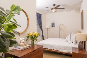A bedroom with a bed, bedside table, lamp, and a ceiling fan.
