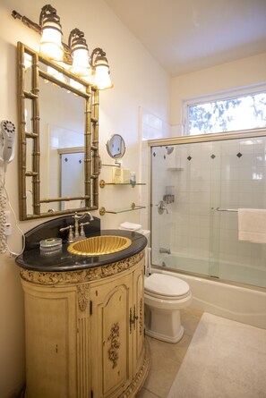 A bathroom with a vanity, sink, mirror, and a glass-enclosed shower.