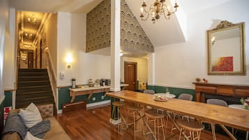 A spacious kitchen with a long wooden table, bar stools, and a staircase leading to an upper level.