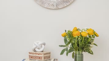 A wooden dresser with a mirror above it, a vase with yellow flowers, and a decorative knot on a box.