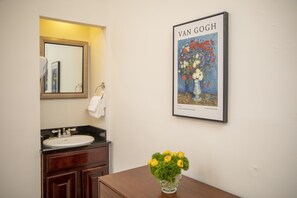 Ein Badezimmer mit Waschbecken, Spiegel und einem gerahmten Van Gogh Gemälde.