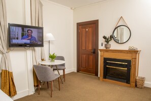 Une chambre d’hôtel équipée d’une télévision, d’une cheminée, d’une table à manger avec des chaises et d’une porte.