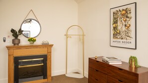 Een kamer met een houten openhaard, een spiegel, een lijstwerk, een vloerlamp en een houten dressoir.